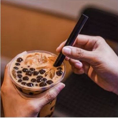 A freshly made milk tea topped with boba, straw going in